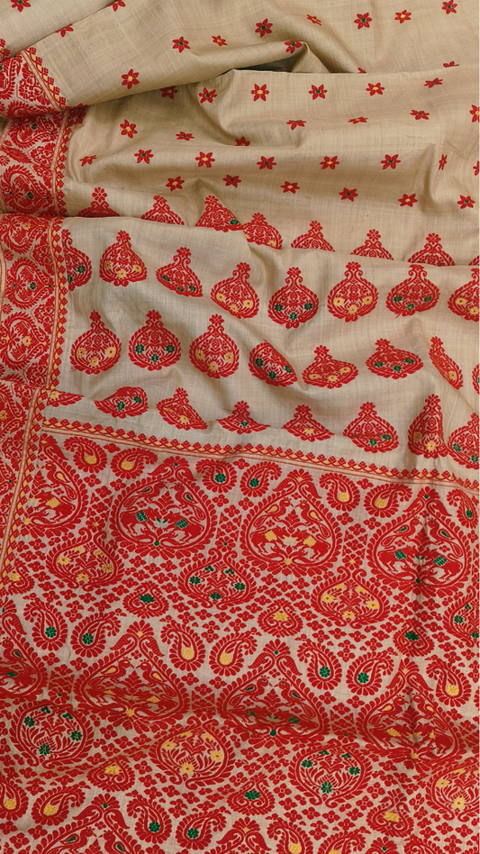 Side view of Assam Muga silk saree highlighting red paisley detailing and green accents.