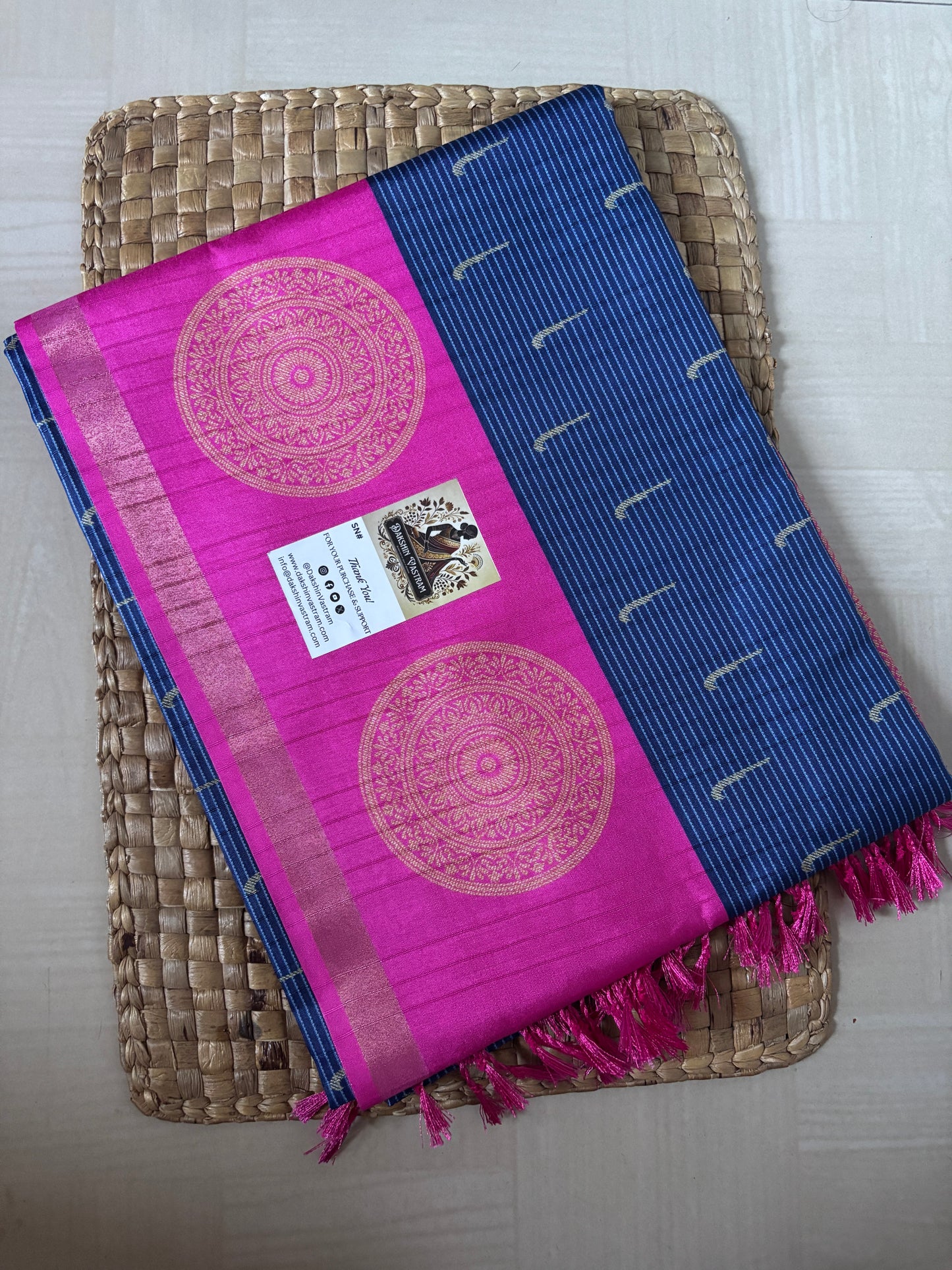 Pink and blue saree with decorative patterns on a woven tray
