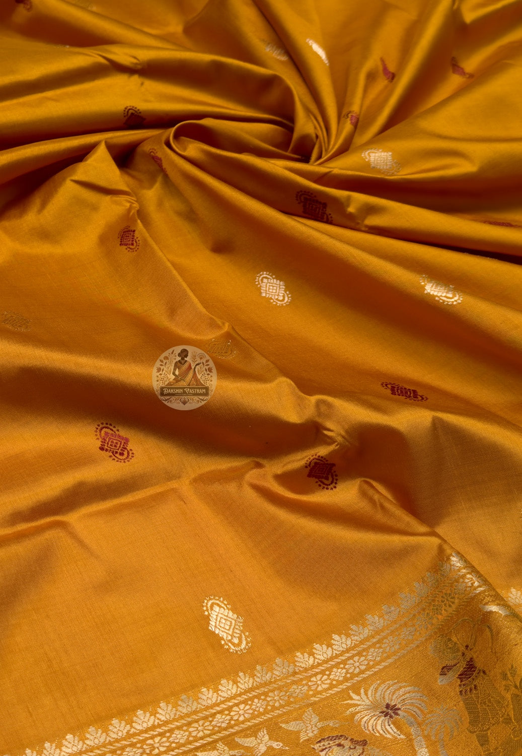 Full saree view highlighting mustard-gold pleats, golden-toned borders and coloured accents in the figurative pallu