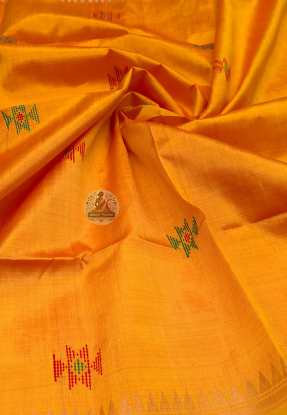 Close up of small multicoloured geometric motifs on the mustard-yellow silk saree body