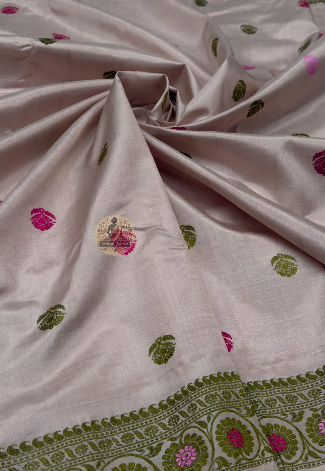 Close up of pink and olive-toned motifs on the taupe Baluchari silk saree body
