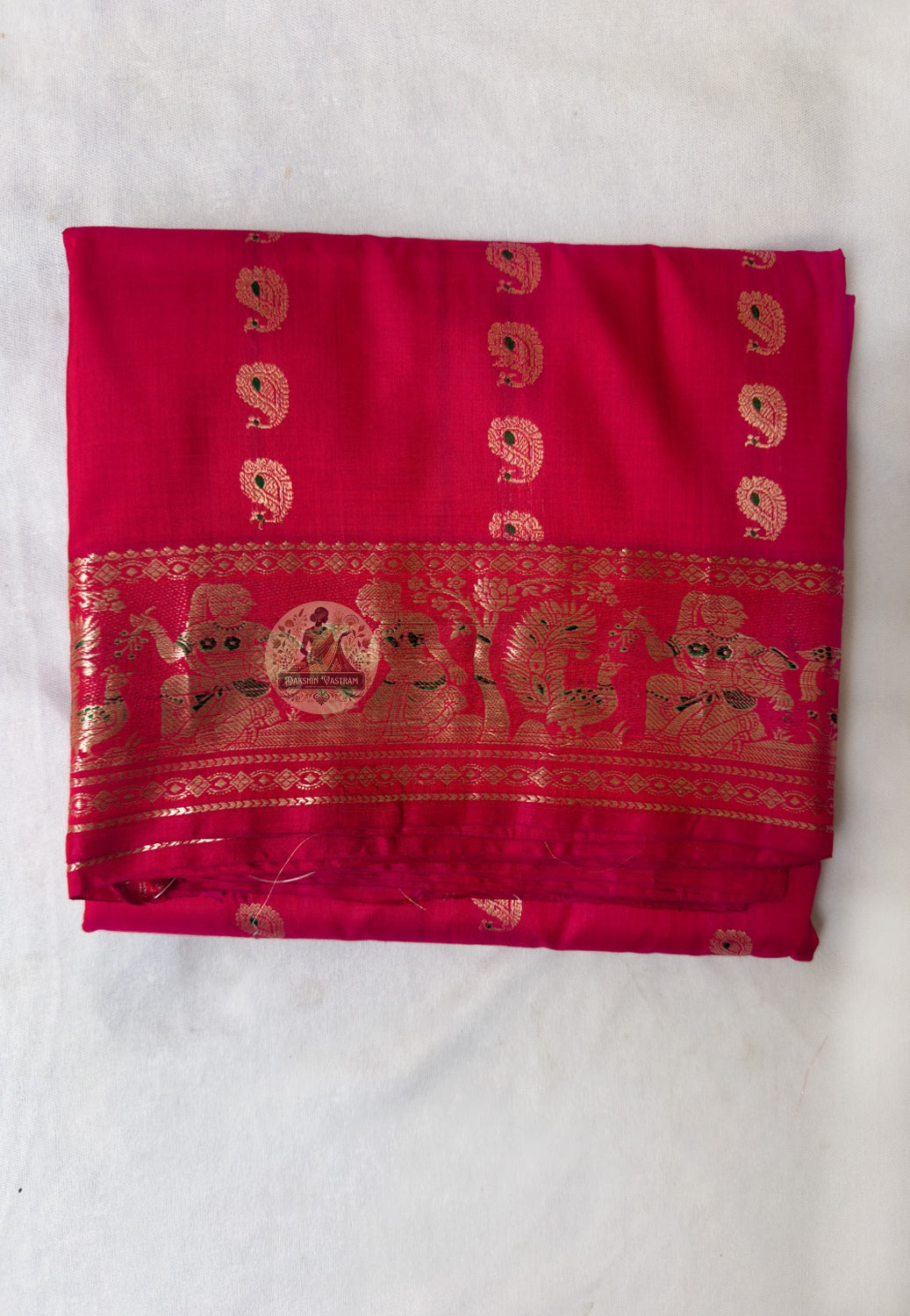 Full flat-lay of Swarnachari pure silk saree with golden zari border, story-holding narrative pallu, buti field in readiness, and matching unstitched blouse piece, West Bengal handloom