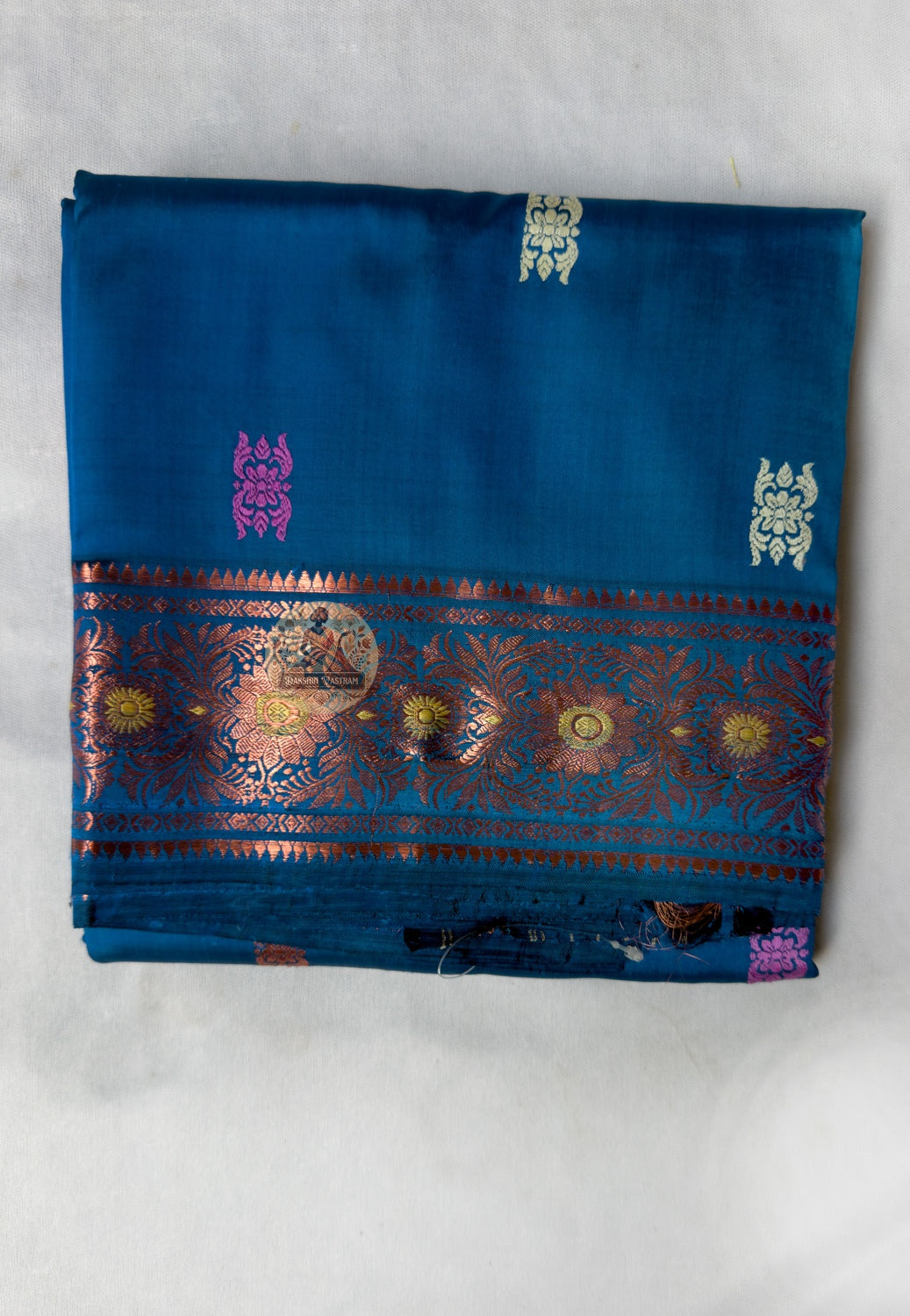 Close-up of premium Swarnachari handloom silk saree body showing warm pure silk ground with fine golden zari butis (small woven motifs) placed with patient precision, each contributing to the whole, Bengal craft