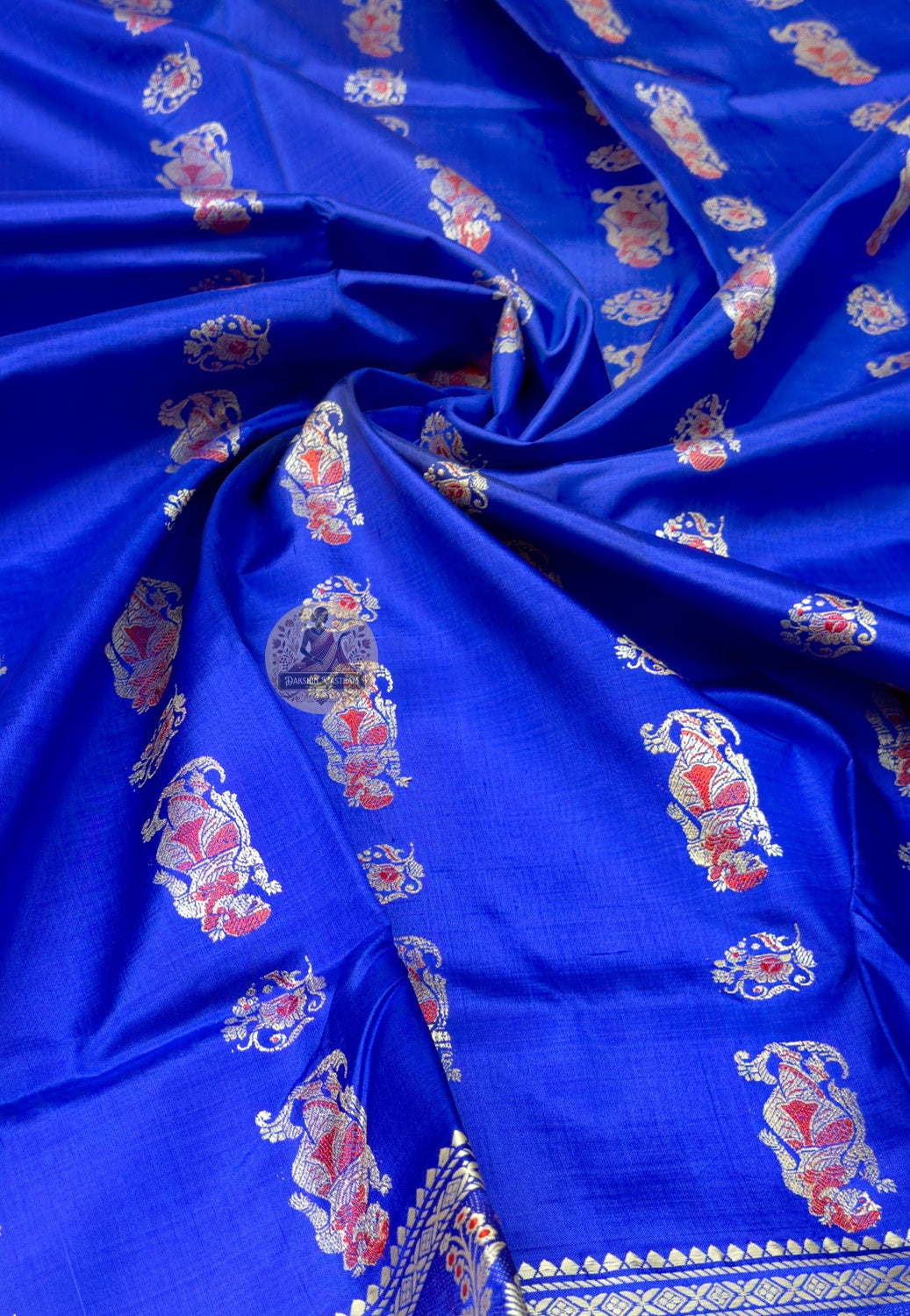 Close up of royal blue Baluchari silk saree pallu with rows of figures and large paisley panels