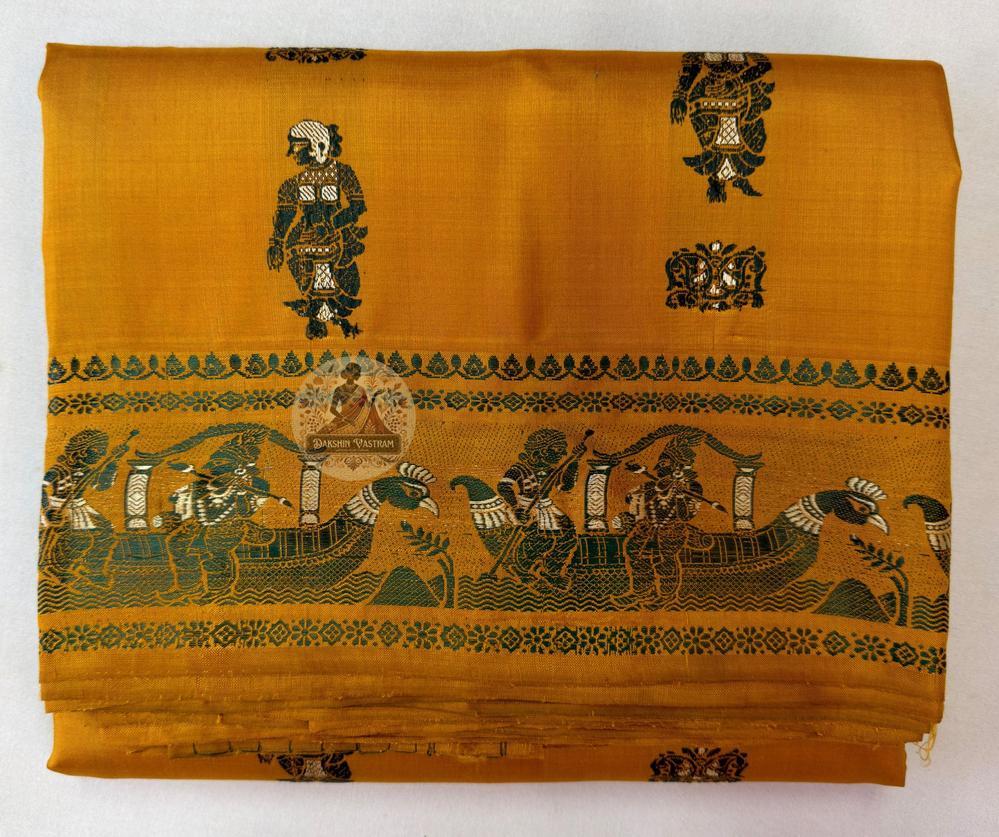 Detailed view of the Baluchari saree border featuring a hand-woven narrative scene of a royal procession with figures, birds and temple motifs in mustard and green silk