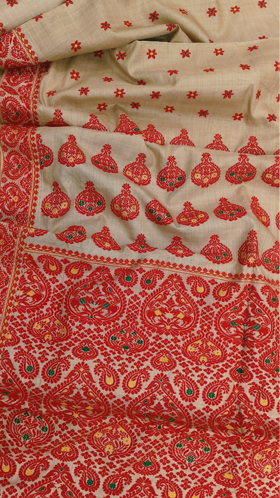 Rear view of beige-gold Assam handloom Muga silk saree with red floral and paisley motifs.