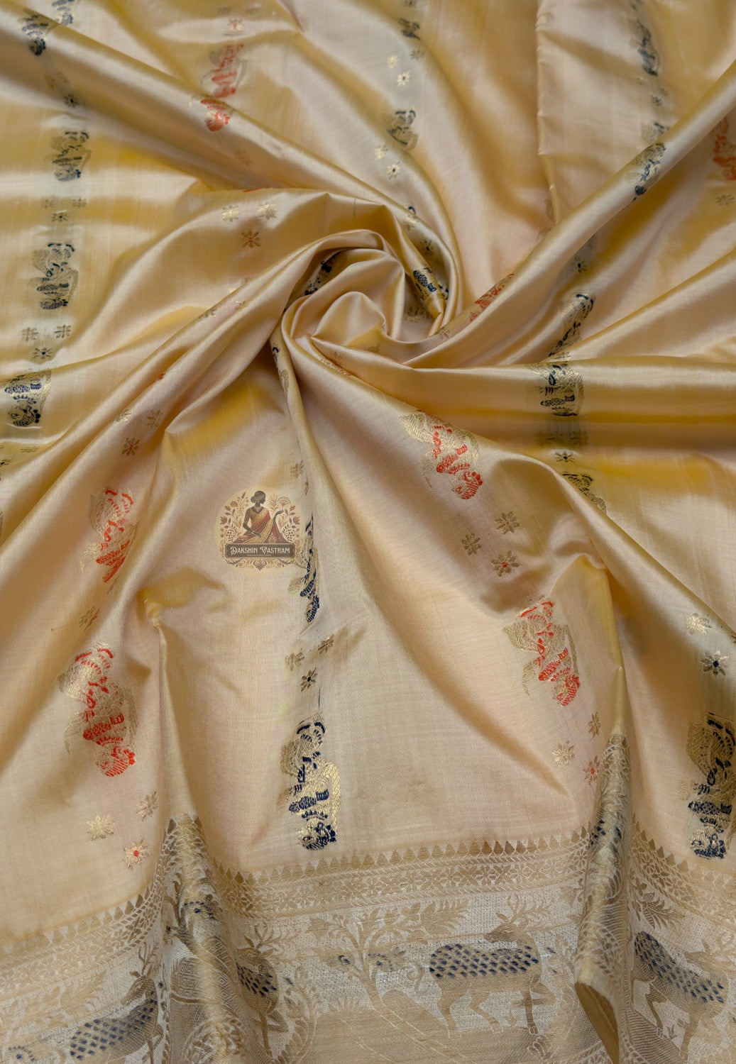 Close up of champagne gold Swarnachari silk saree pallu with coral-accented figures inside oval frames