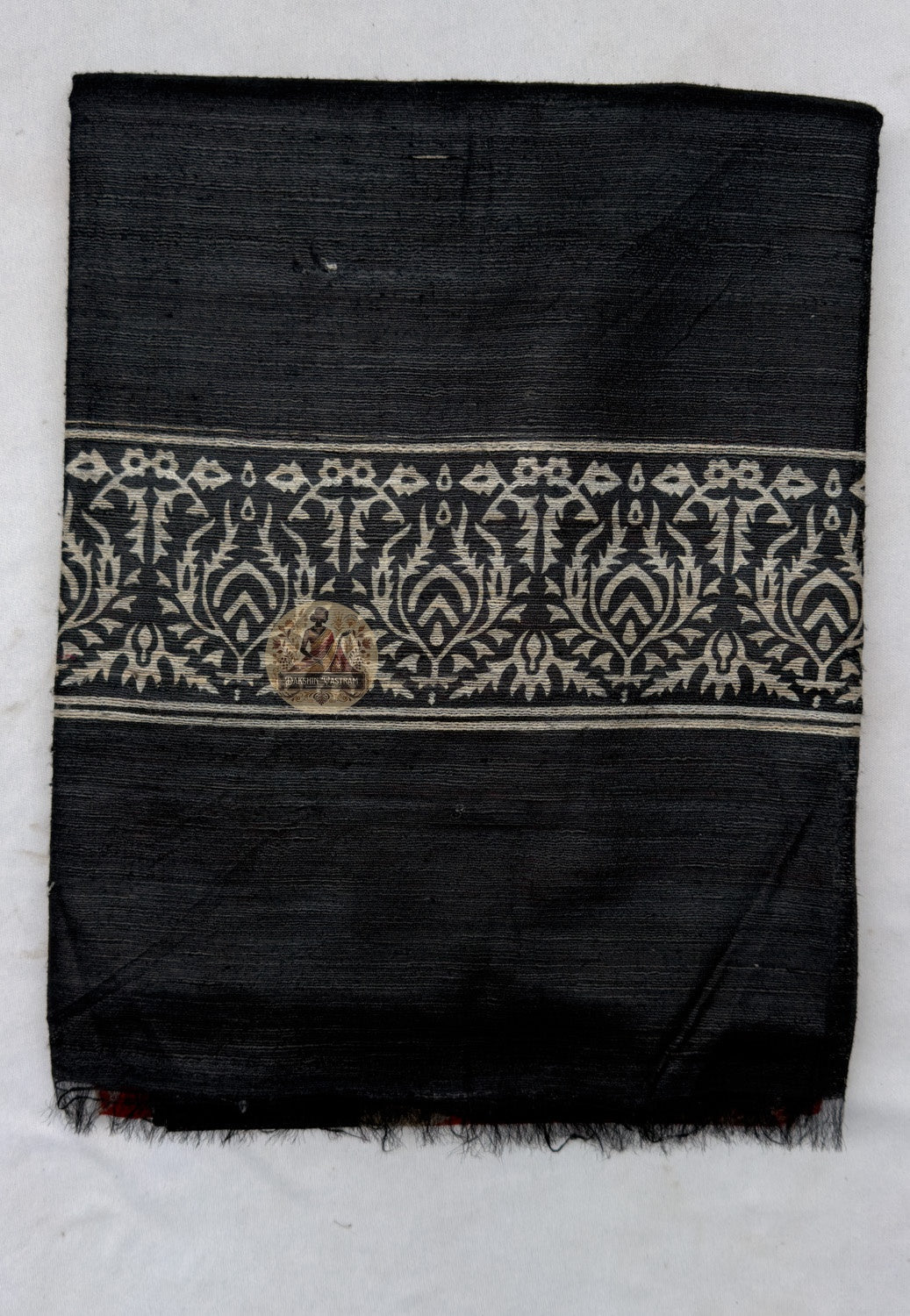 Close up of the black pallu featuring pale scrolling botanical bands and triangular accents along the red section