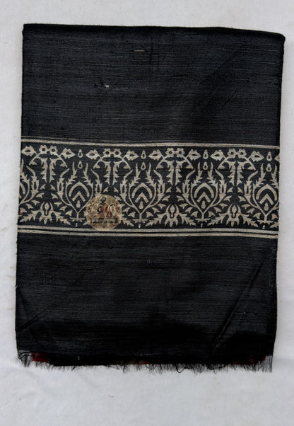 Close up of the black pallu featuring pale scrolling botanical bands and triangular accents along the red section