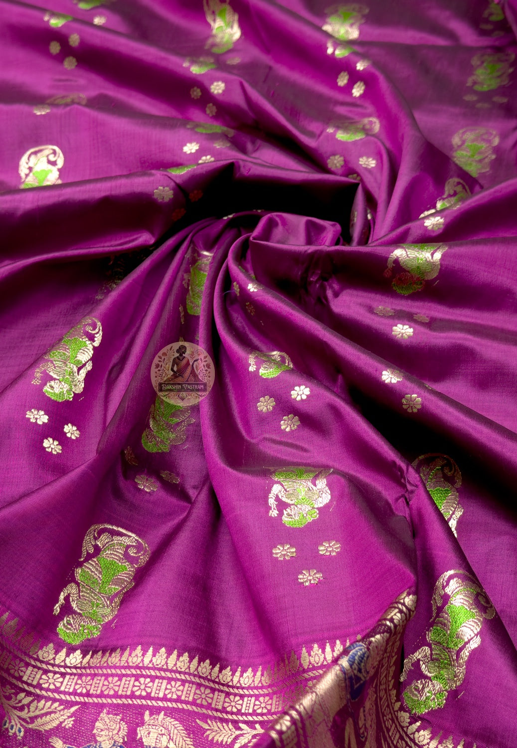 Close up of plum magenta Swarnachari silk saree pallu with woven figures beneath arch-shaped frames