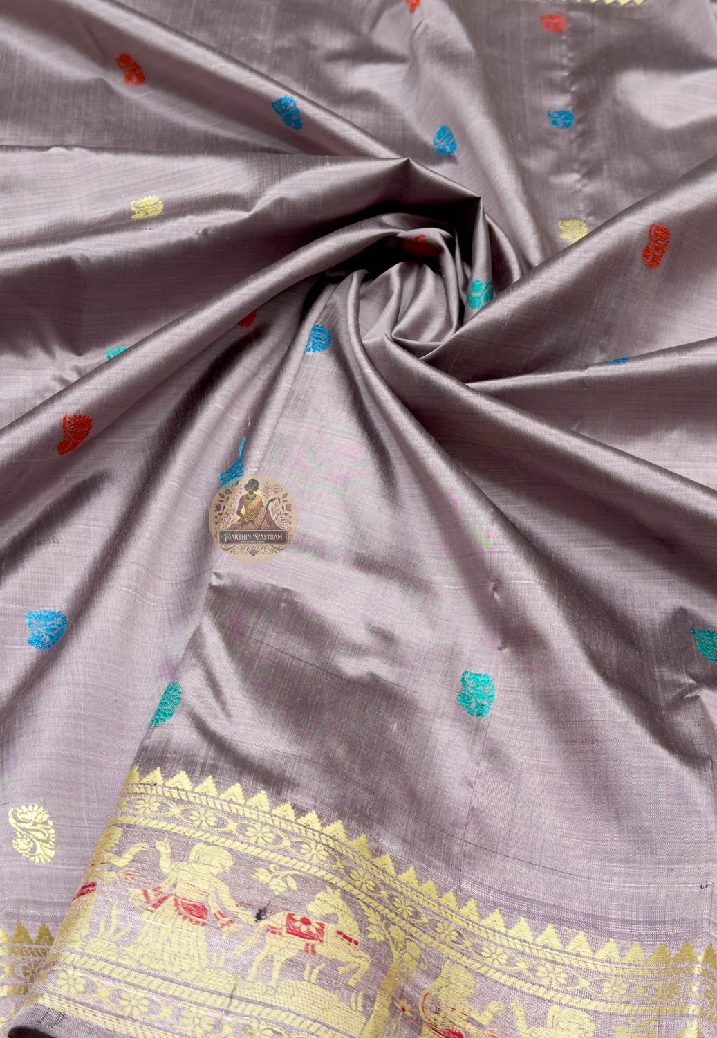 Close up of the red narrative pallu featuring figures, wheeled vehicles, animals and ornamental bands