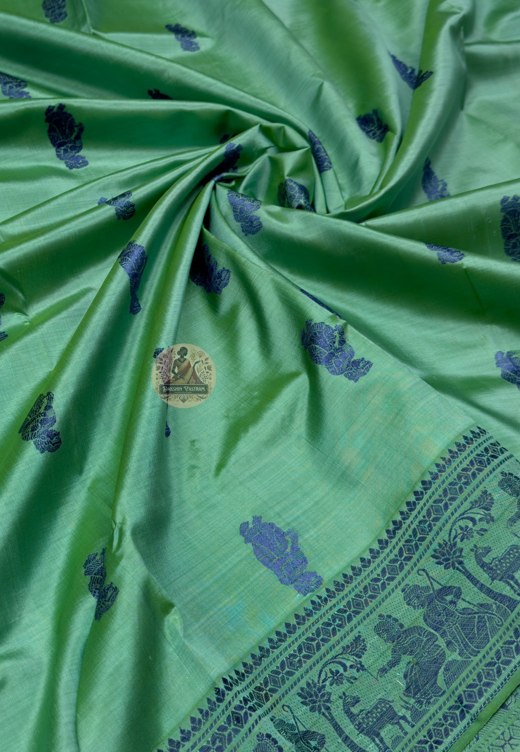 Close up of blue ornamental motifs spaced across the green silk body