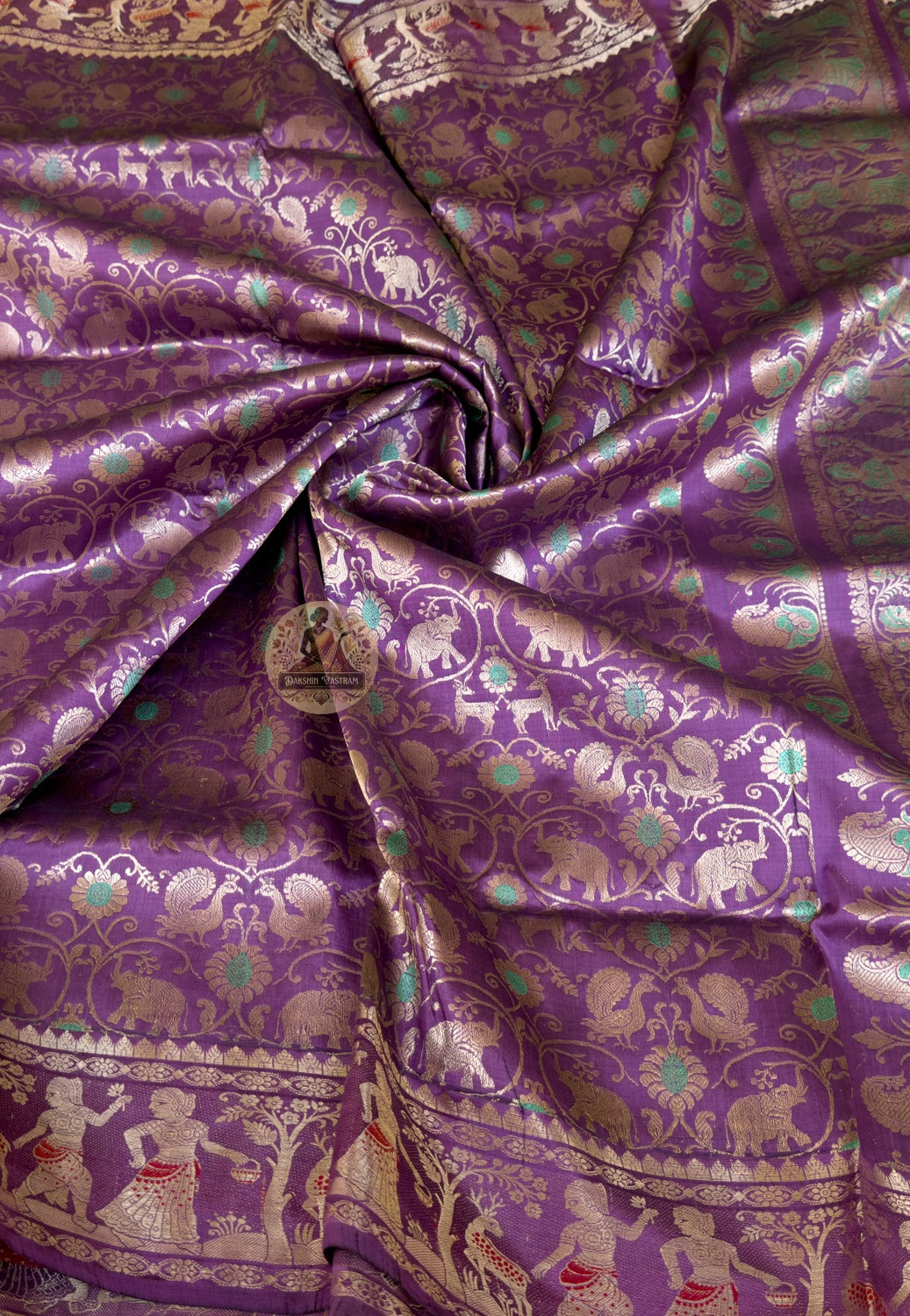 Full flat-lay of premium Swarnachari pure silk saree with golden zari narrative border, unified story pallu, precisely spaced buti field, and matching unstitched blouse piece, West Bengal handloom