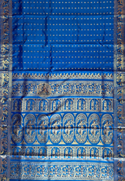 Close-up of blue Swarnachari silk saree weave showing golden zari mythology and royal Bengal court motifs woven thread by thread on deep indigo pure silk ground handloom