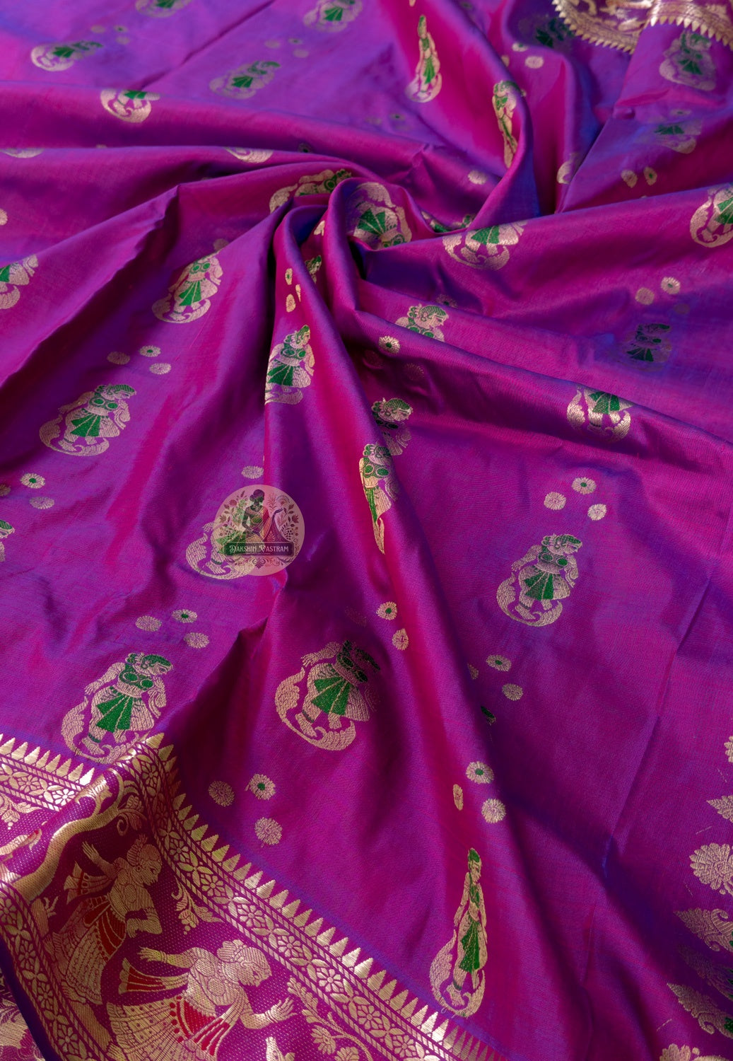 Rear view of purple Swarnachari silk saree showcasing fully expressed pallu with mythology and Bishnupur temple art golden zari compositions deepening in warm pandal and reception light
