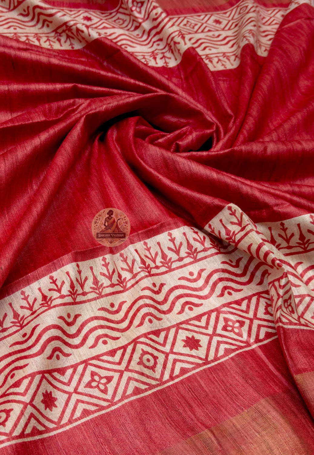 Close up of the red Ghicha Tussar saree pallu featuring female figures in pale panels and circular motifs