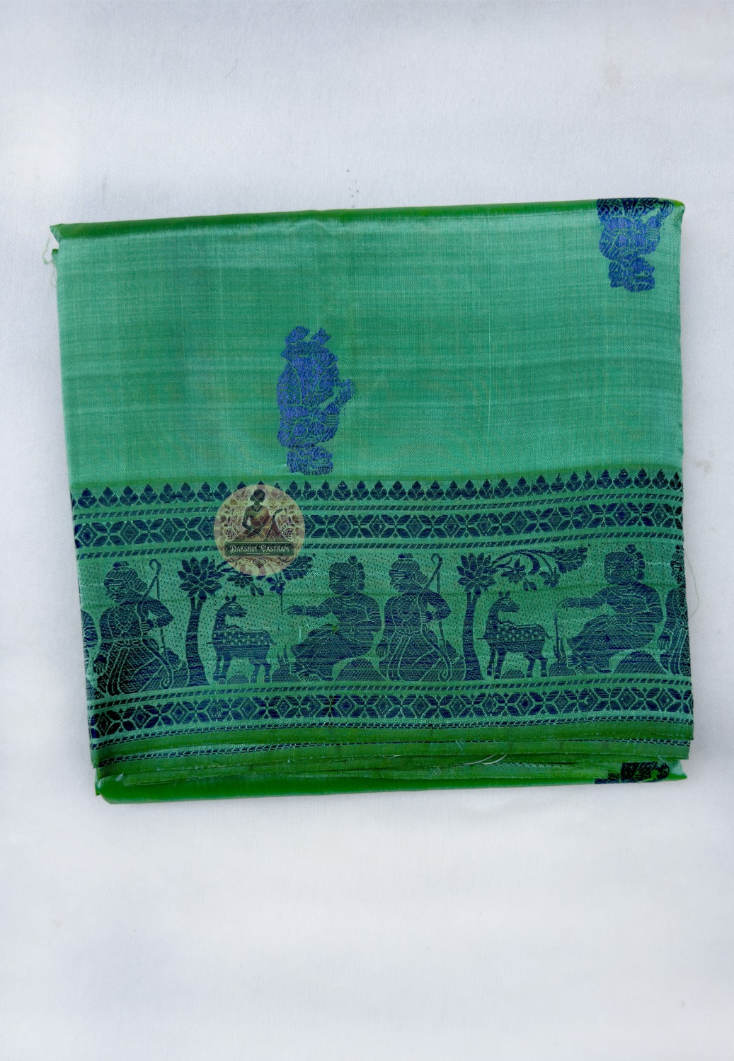 Close up of woven figures in elongated frames and horizontal narrative panels on the blue-and-green pallu
