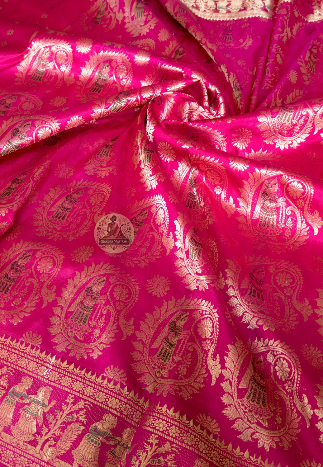 Close-up of pink Swarnachari silk saree weave showing golden zari mythology figures Malla court motifs and Bishnupur temple art patterns warming and deepening against pink silk ground