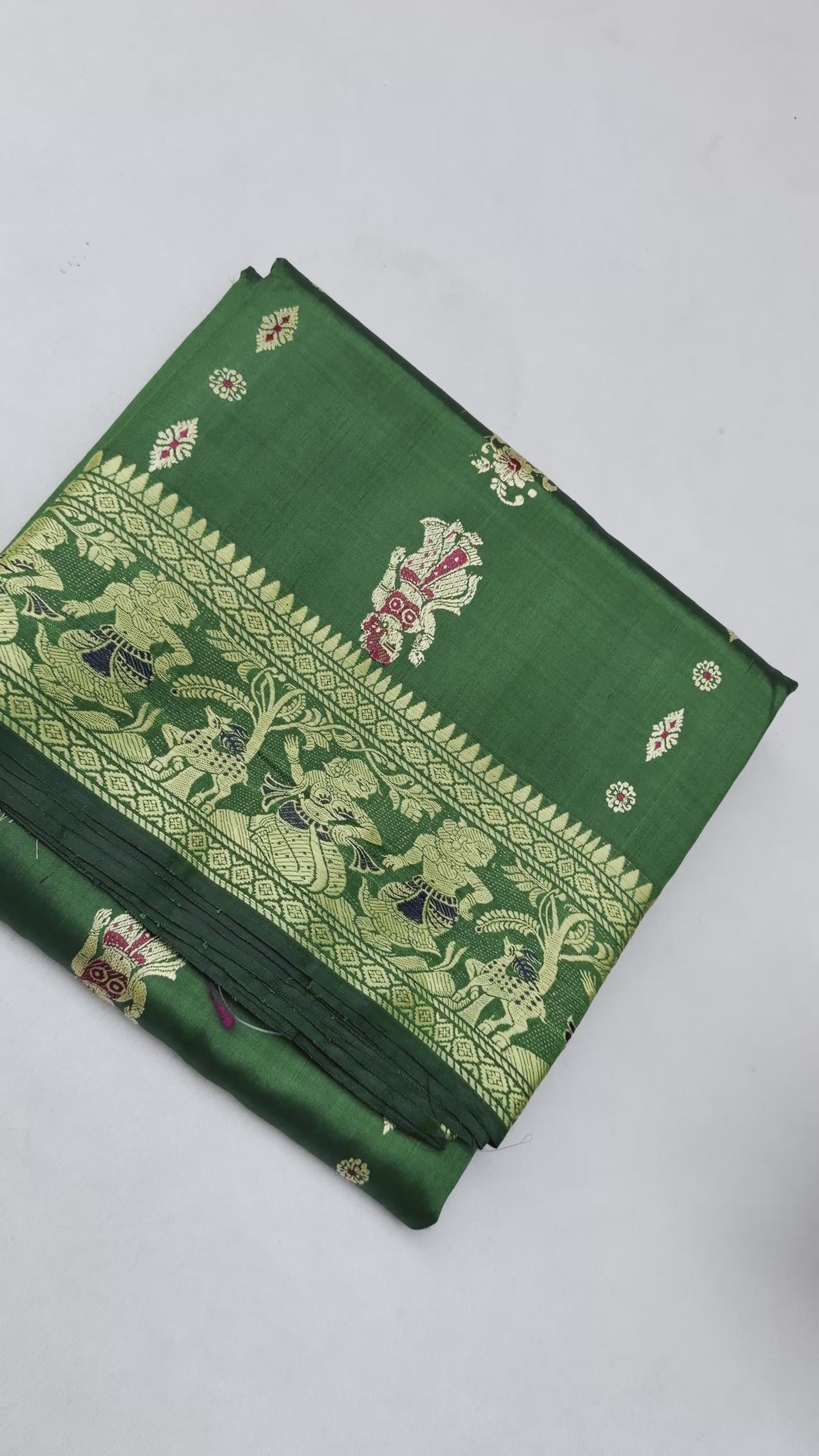 Full saree view highlighting emerald green pleats, gold-toned borders and the figurative paisley pallu