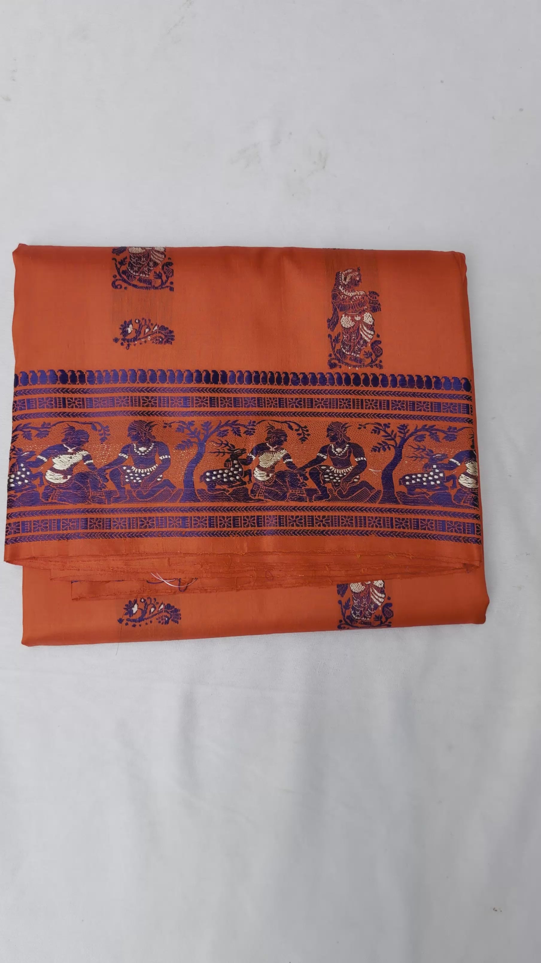 Full saree view highlighting orange pleats and the elaborate figurative pallu⠋